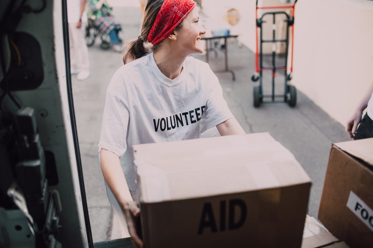 Smiling volunteer woman carrying aid boxes for a charity event.